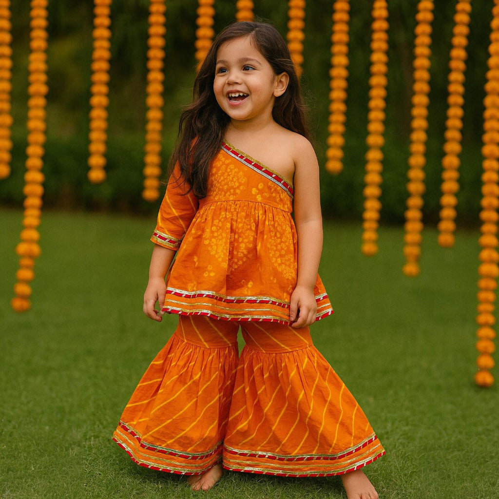 Girl wearing an Orange Bandhani Cotton One-Shoulder Kurta with Sharara