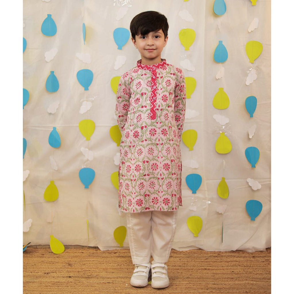 Boy wearing a floral kurta with white pants.