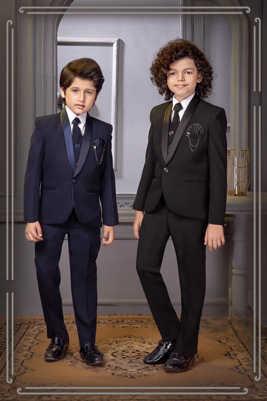 Two boys wearing black and navy tuxedo-style suits with lapel chain