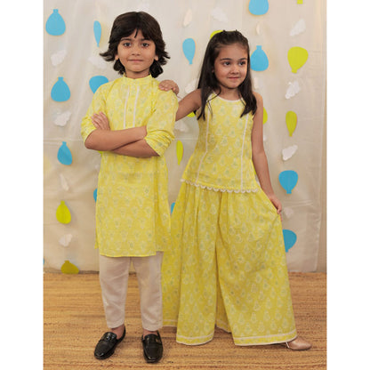 Siblings twinning in a matching yellow outfit.